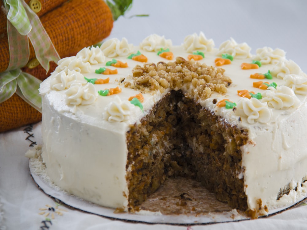 A carrot cake with cream cheese icing, cut into at the counter